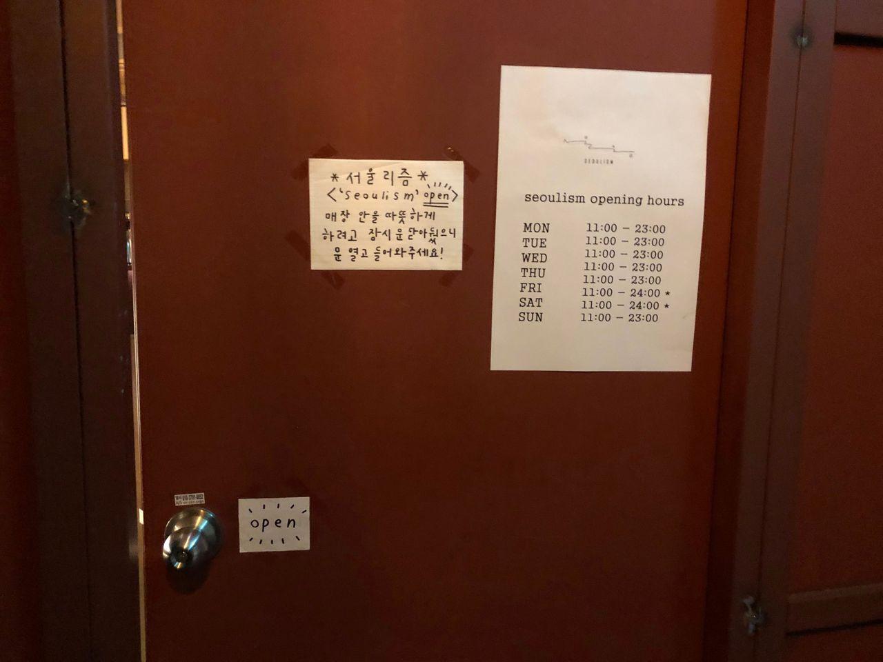 ソウリズムカフェのドアと営業時間が記載された紙の写真